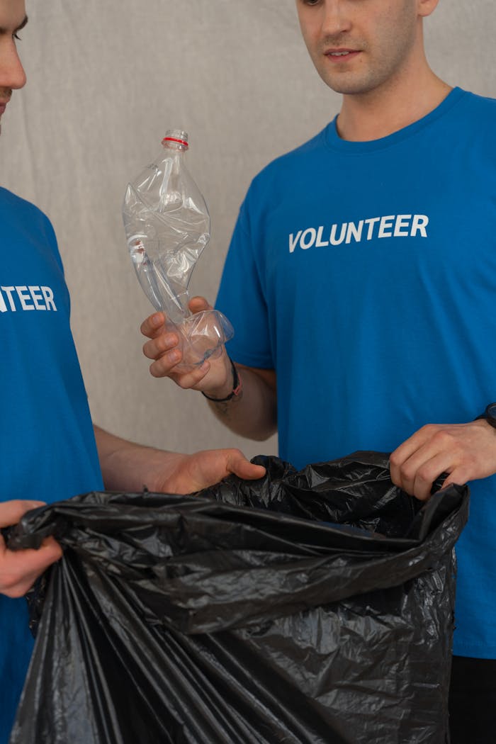 Two volunteers sorting plastic bottles into a bag, promoting environmental conservation.
